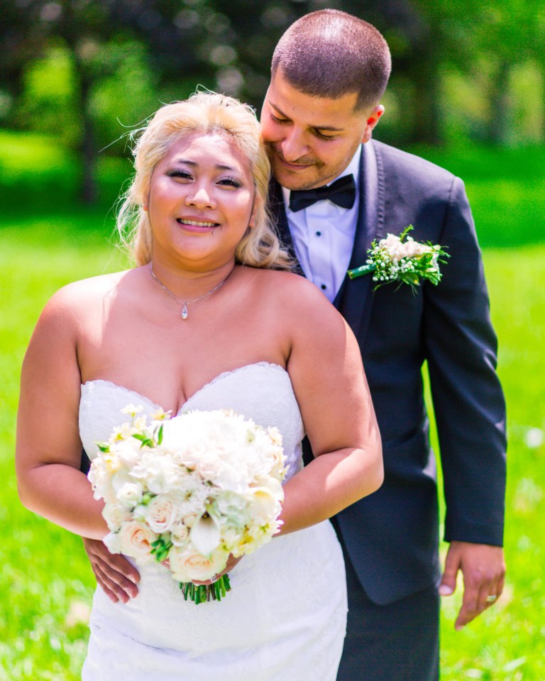 A relaxed garden portrait of the couple with a white bouquet