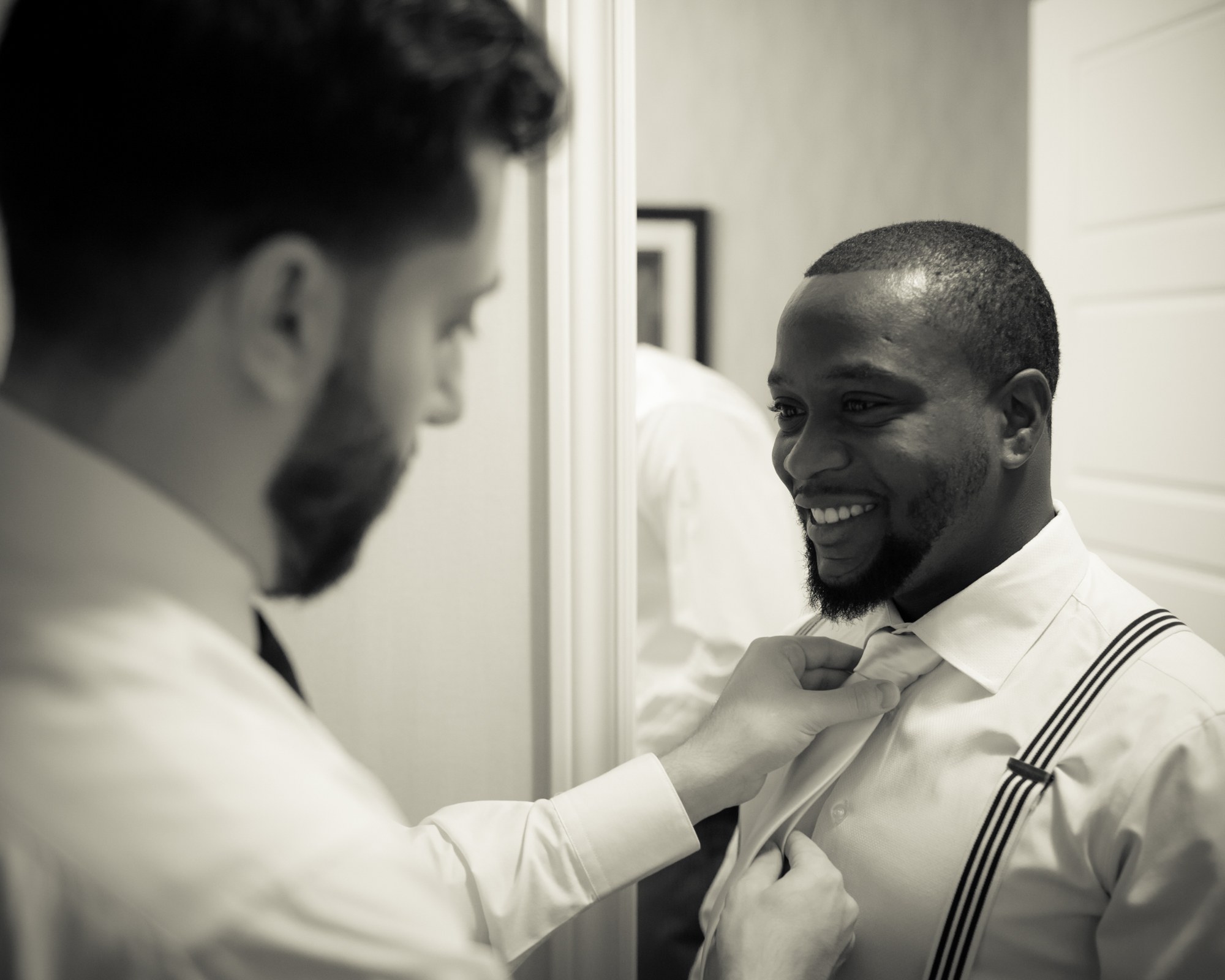 A friend helping the groom with his tie