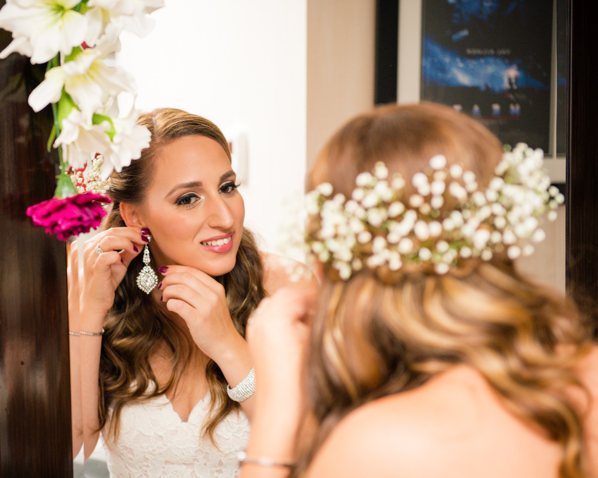 Bride putting on earrings in front of a mirror