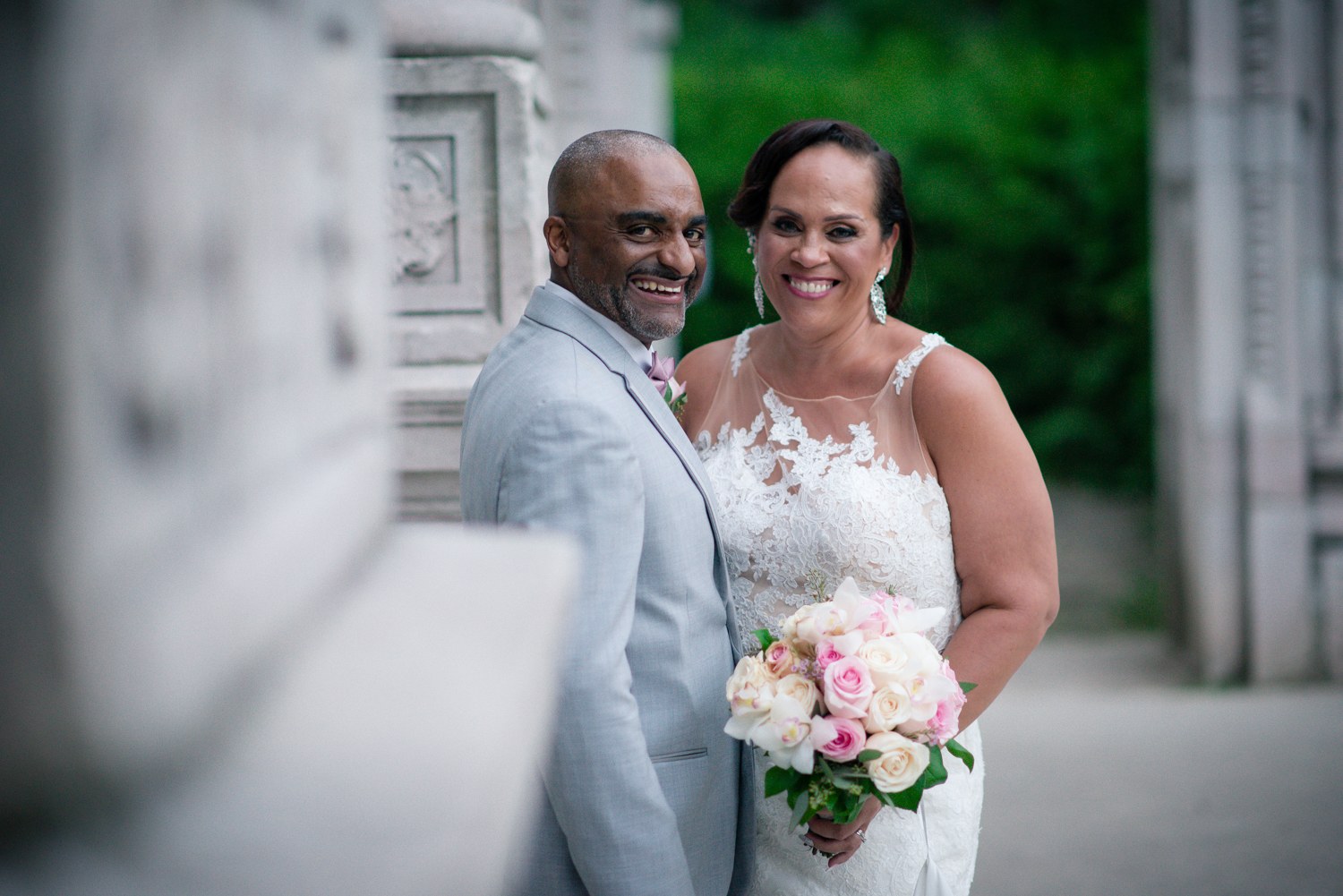 Newlyweds smiling together beside carved stonework