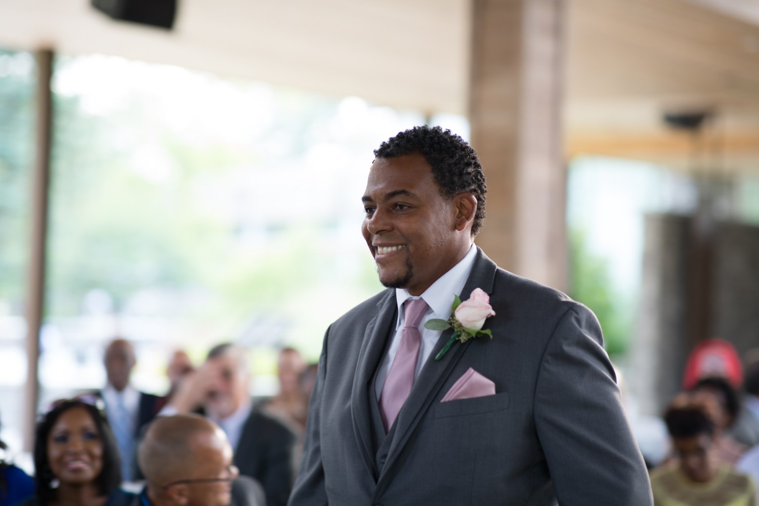 Groom smiling as guests look on