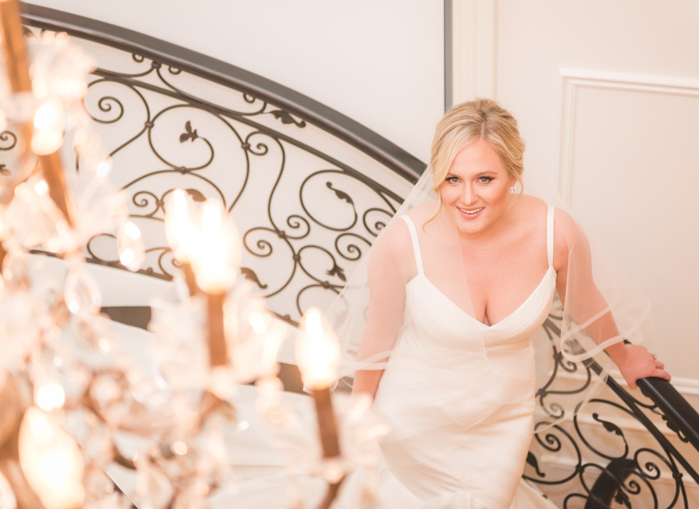 Bride smiling on a staircase beside a chandelier