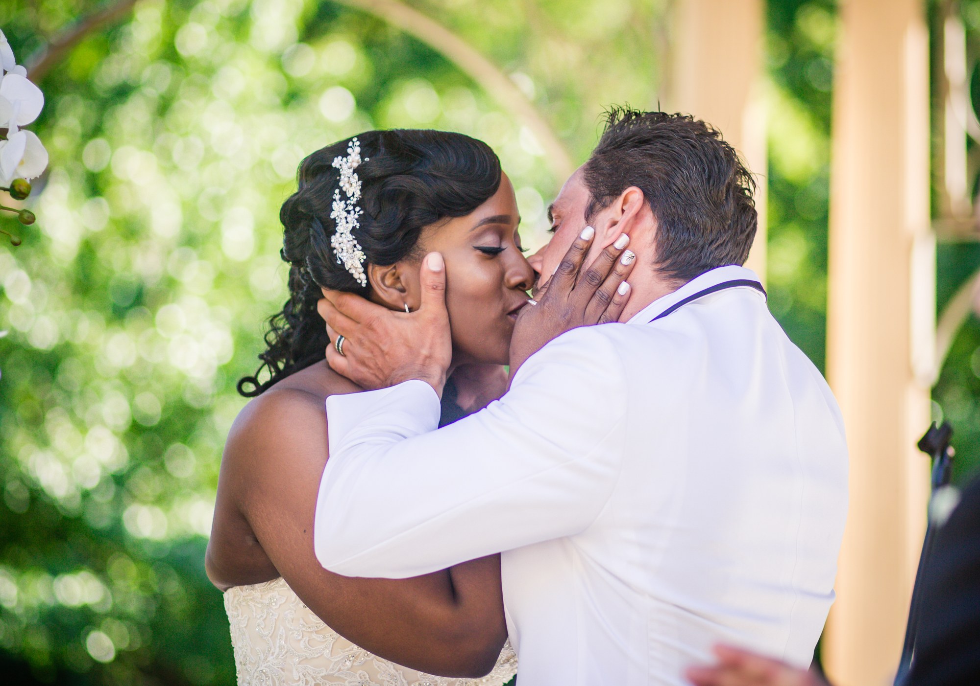 A kiss beneath a flower-covered ceremony arch